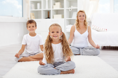 kids doing yoga relaxing exercise with instructor
